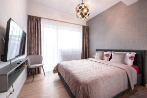 a bedroom with a bed and a flat screen tv at Mountain Breeze ApartTerrace in Braşov