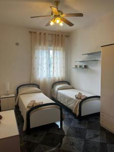 two beds in a bedroom with a ceiling fan at Sempre verde in Agnone Bagni