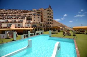 a large swimming pool in front of a large building at Apartamento PinkFloyd im Palm Garden in Morro del Jable