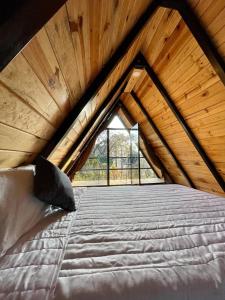 a large bed in a wooden attic with a window at Portocielo Cabin in La Marquesa