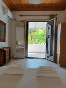 ein Schlafzimmer mit zwei Handtüchern auf einem Bett mit Glasschiebetür in der Unterkunft Lovely Sunrise apartment by the beach in Methoni
