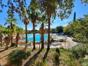 un resort con piscina e palme di La villa Charles Grimaud Les Restanques Golf de Saint Tropez a Grimaud