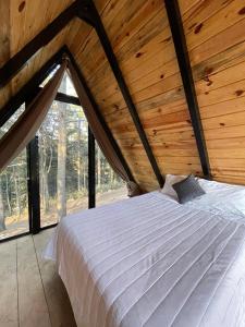 a bedroom with a white bed in a wooden ceiling at Portocielo Cabin in La Marquesa