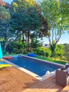 a swimming pool in a backyard with a wooden deck at LA CLOSERIE DE NOINTOT in Nointot