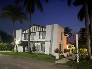 a white house with palm trees in front of it at Peñon Confortable Casa Para Descansar y Disfrutar in Girardot