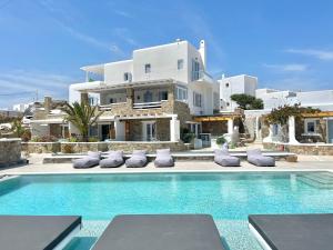 a villa with a swimming pool in front of a house at Crystal Suites in Mýkonos City