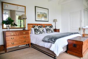 een slaapkamer met een bed, een dressoir en een spiegel bij The Knoll Historic Guest Farm in Hilton