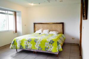 a bedroom with a bed with a yellow blanket and a window at Casa Real Palo Gacho in Emiliano Zapata