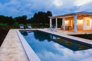 uma piscina com cadeiras e uma casa em Trullo EVO con piscina privata em Ostuni