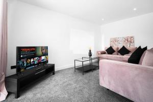 een woonkamer met een bank en een flatscreen-tv bij Cosy 3 Bed House/Free Parking/Fast Wi-Fi/Sleeps 8 in Bilston