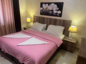 a bedroom with a pink bed with two pillows at Suzan Hotel Apartments in Amman