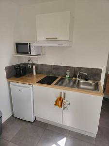 a kitchen with white cabinets and a sink and a microwave at Le Castetnau - securise - Proche Halles de Pau in Pau