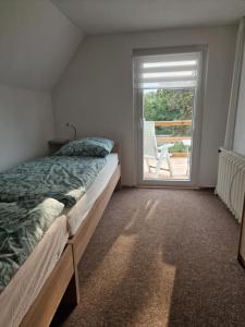 1 dormitorio con 1 cama y ventana con silla en Ferienhaus Kallmeyer, en Parey
