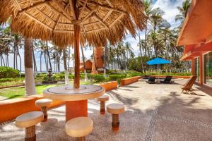 un patio con mesa y taburetes bajo una sombrilla de paja en Villas San Vicente en Acapulco