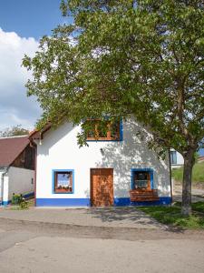 biały dom z niebieskimi oknami i drzewem w obiekcie Apartmán Na vinařské stezce w mieście Velké Bílovice