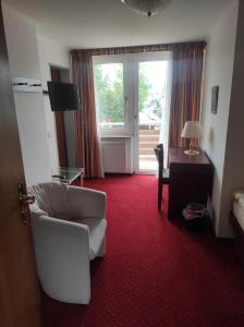 a living room with a chair and a desk and a window at Hotel Aura am Schloss in Bad Pyrmont +12 photos
