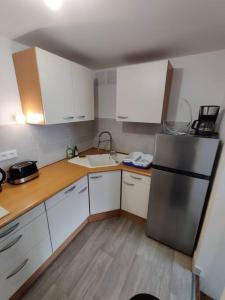 a kitchen with white cabinets and a stainless steel refrigerator at Le TROPICA Appartement 2 chambres, plein Sud centre ville de VITRÉ in Vitré