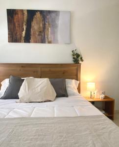 una camera da letto con un letto bianco con un dipinto sul muro di Casa Isa - Aire acondicionado - Piscina - Candelaria - Tenerife a Candelaria