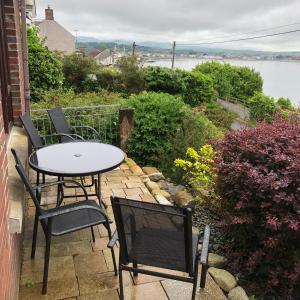 a table and chairs on a patio with a view of the water at Stunning Sea view apartment absolute top quality 100s of 5 star reviews You will not be disappointed in Widows Row