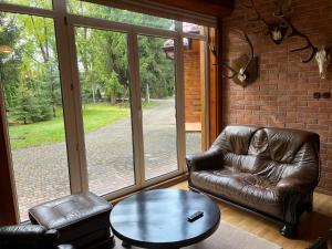 a living room with a leather couch and a table at Domek Myśliwski w Spale in Spała