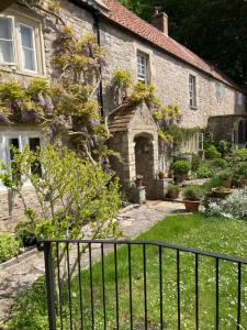 uma velha casa de pedra com uma cerca em frente em Maplestone em Shepton Mallet