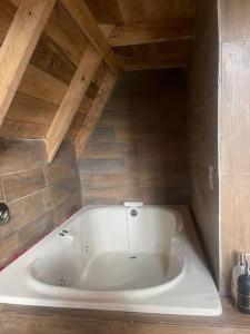 a large white bath tub in a room with wooden ceilings at Portocielo Cabin in La Marquesa