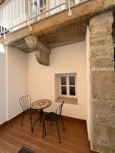 a table and chairs in a room with a stone wall at Pátio 29 - Guest House in Viana do Castelo