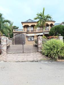 a large house with a gate and palm trees at Cambridge mi casa ur casa with pool and beach access in Runaway Bay