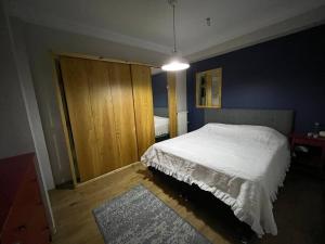 een slaapkamer met een wit bed en een houten kast bij Bosphorus waterfront flat, Cengelköy in Istanbul