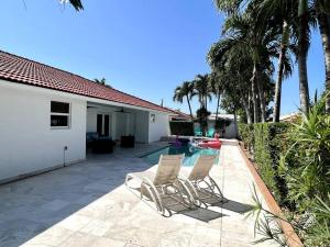 um pátio com 2 cadeiras e uma piscina em Sunny Getaway: Relaxing Miami Home em Tamiami