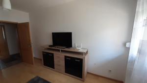 sala de estar con TV de pantalla plana en un soporte en APARTMAN AMSTERDAM en Brčko