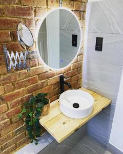 Un baño con un lavabo blanco y un espejo. en Cooden Cottage, en Bexhill-on-Sea