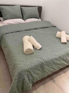 Una cama verde con dos toallas enrolladas. en Designed Central Apartment, en Volos