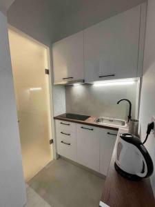 una pequeña cocina con armarios blancos y licuadora en Designed Central Apartment, en Volos