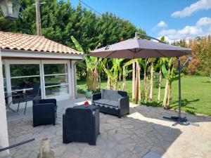 a patio with two chairs and an umbrella at Detente au pays de Lauzun in Saint-Colomb-de-Lauzun