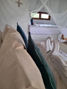 a bed with white sheets and pillows in a room at Beekite Wind Village in Luis Correia