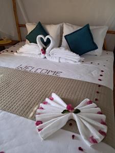 two beds with white towels and two swans on them at Beekite Wind Village in Luis Correia