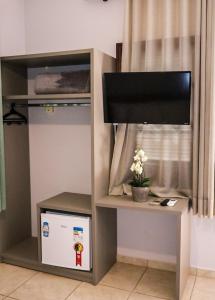 um quarto com uma televisão e uma janela com um computador e um tvictericter em Shellter Hotel em Holambra