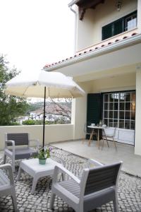 a patio with a table and chairs and an umbrella at Casa Do Shon in Óbidos
