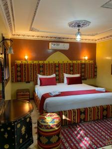 a hotel room with two beds and a table at Dar Alfourssane Ferme d’hôte in Ouarzazate