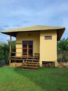 a small yellow house with a porch and a fence at Beekite Wind Village in Luis Correia