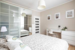 a white bedroom with a bed and a desk at Apartament REZYDENCJA MARINA in Gdańsk