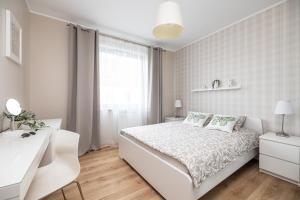 a white bedroom with a white bed and a window at Apartament REZYDENCJA MARINA in Gdańsk