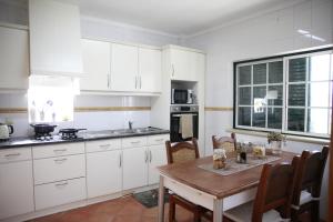 una cocina con armarios blancos y una mesa con sillas. en Casa Do Shon, en Óbidos