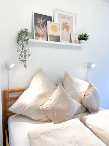ein Schlafzimmer mit einem Bett mit weißen Kissen und einem Regal in der Unterkunft NAMI - ROBIN - Helle Apartments mitten in der Stadt in Memmingen