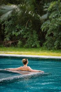 una mujer en el agua en una piscina en Moodhoian Riverside Resort & Spa en Hoi An