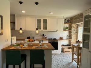 uma cozinha com armários brancos e uma ilha com cadeiras verdes em Casa La Antigua Escuela em Mondariz