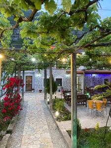 um jardim com um pátio com uma mesa e flores em Kulla e Vjeter (Bar Restaurant, Guesthouse, Parking and Camping) em Koman