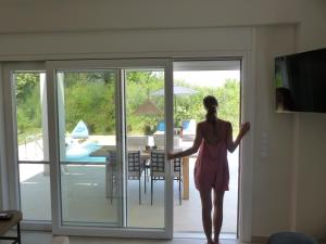 a woman in a pink dress walking out of a door at Casa O' - Moderne Villa mit großer Terrasse und privatem Swimmingpool in Skala Potamias