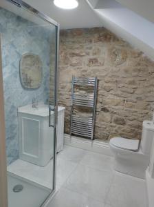 bagno con lavabo, servizi igienici e parete in pietra. di Prizon House Balla a Mayo